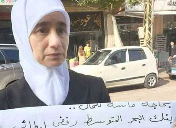 مربية صيداوية ترفع لافتة أمام أحد المصارف في صيدا ..